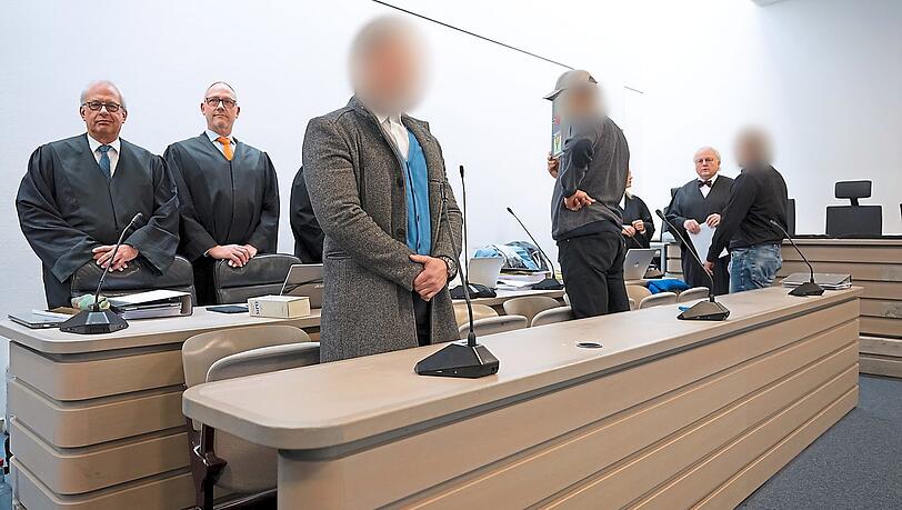 Die wegen schweren Bandendiebstahls angeklagten Männer stehen vor Prozessbeginn im Gerichtssaal.