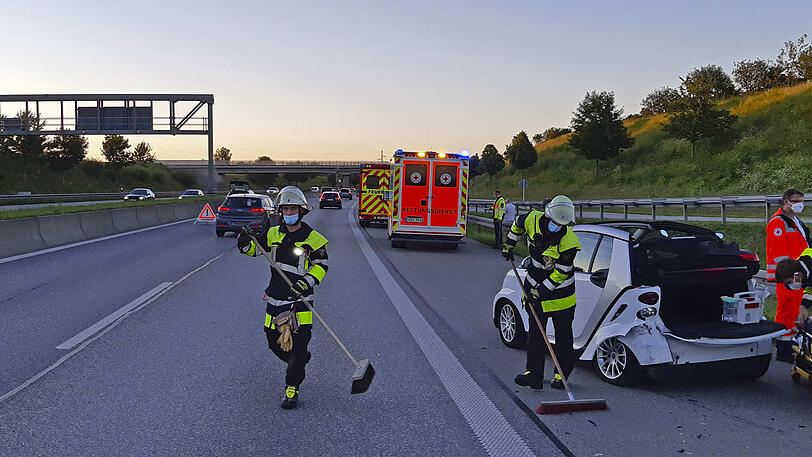 Einsatzkräfte der Feuerwehr säubern den Unfallort auf der A99.