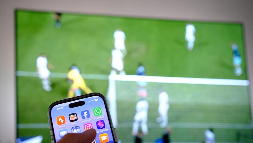 Nebenbei mal daddeln: W&auml;hrend das Fu&szlig;ballspiel l&auml;uft, schauen viele Zuschauer nebenbei aufs Handy. (Symbolbild)