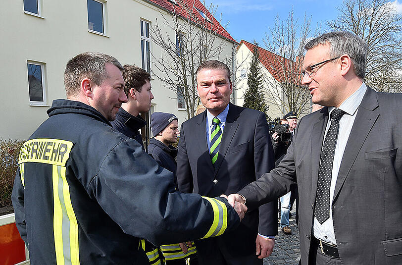 Der Landrat des Burgenlandkreises, Götz Ulrich (CDU, r) und Sachsen-Anhalts Innenminister Holger Stahlknecht im Gespräch mit Feuerwehr und Polizei vor dem ausgebrannten Flüchtlingsheim in Tröglitz.