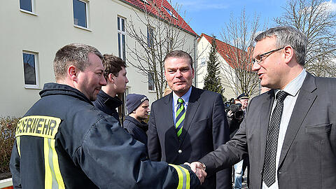 Der Landrat des Burgenlandkreises, Götz Ulrich (CDU, r) und Sachsen-Anhalts Innenminister Holger Stahlknecht im Gespräch mit Feuerwehr und Polizei vor dem ausgebrannten Flüchtlingsheim in Tröglitz.