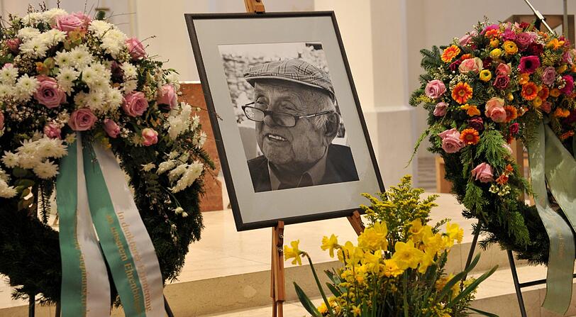 Kränze und ein Foto Otfried Preußlers stehen am 01.03.2013 in der Stadtpfarrkirche St. Nikolaus in Rosenheim bei der Trauerfeier für den verstorbenen Kinderbuchautor.