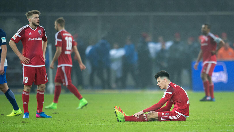 Nach dem Spiel gegen Hertha BSC Berlin sitzt Ingolstadts Alfredo Morales auf dem Spielfeld, sein Mitspieler Robert Leipertz (l) steht auf dem Platz.