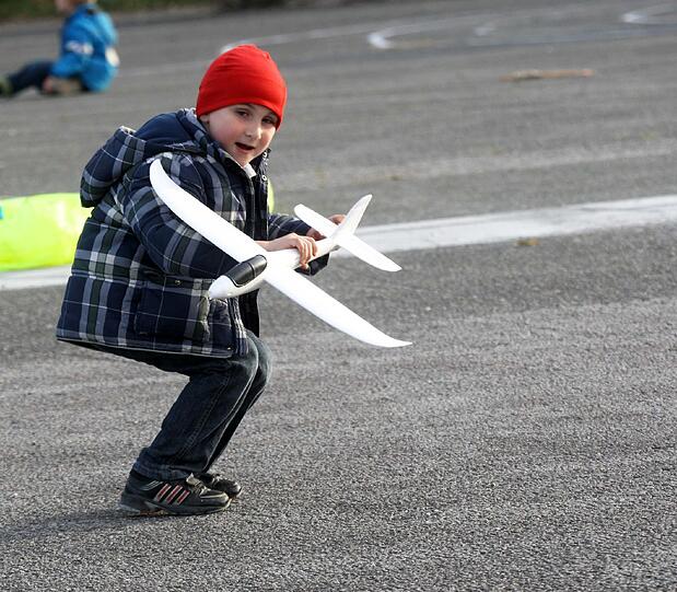 Jeder fängt mal klein an: Ein Bub mit einem Segelflugzeug, Antrieb per Hand und Wind.