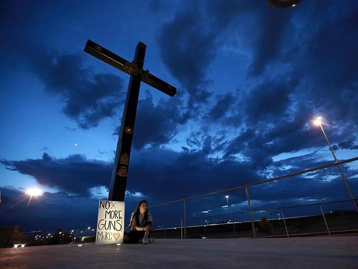 Eine Frau sitzt in El Pasos mexikanischer Nachbarstadt Juarez neben einem Schild mit der Aufschrift "No more Guns, make Love".