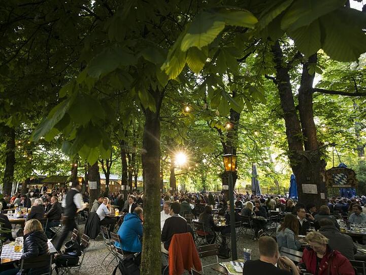 Besucher genießen in einem Biergarten die untergehende Sonne. Foto: Peter Kneffel/Archiv
