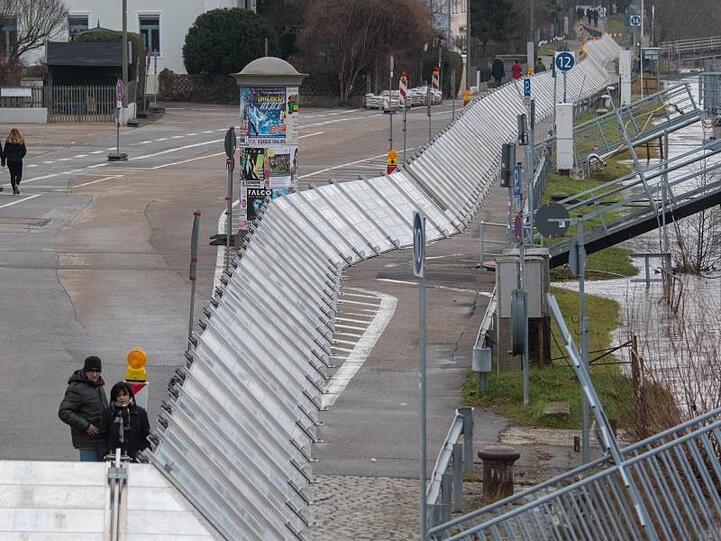 Schutzwände stehen in Regensburg am Ufer der Hochwasser führenden Donau. Foto: Armin Weigel/Archivbild
