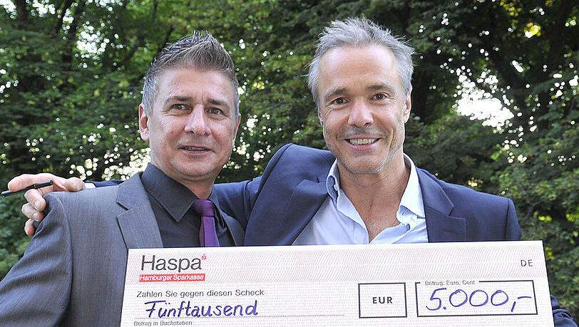 Ulfert Böhme (li) und Hannes Jaenicke halten stolz den Scheck über 5000 Euro in die Kamera Ulfert Böhme (li) und Hannes Jaenicke halten stolz den Scheck über 5000 Euro in die Kamera
