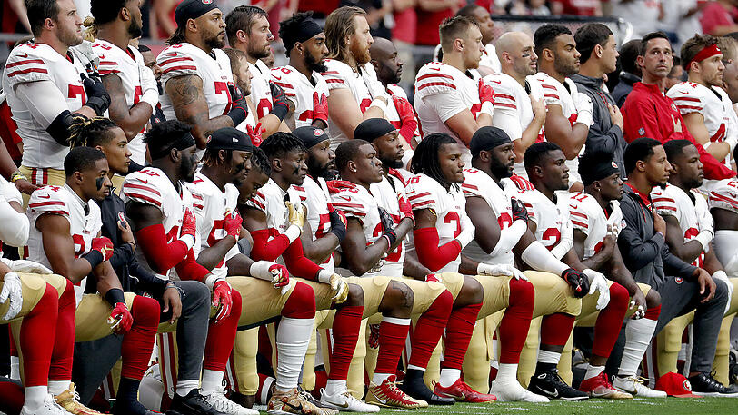 Demonstrative Aktion gegen Rassismus und Polizeigewalt: Die San Francisco 49ers knien teilweise beim Abspielen der Nationalhymne nieder. Präsident Donald Trump diffamiert sie dafür als "Hurensöhne".