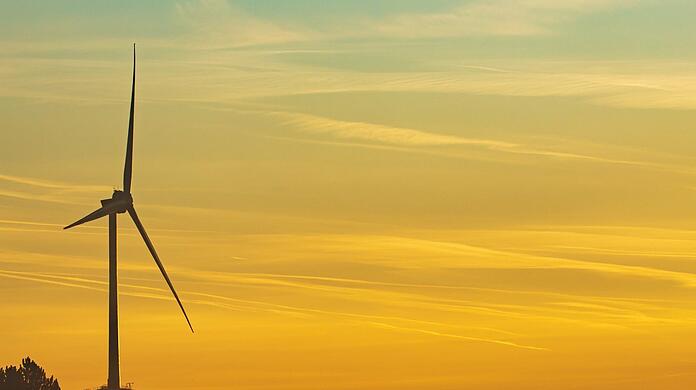 Nebelschwaden liegen bei Sonnenaufgang in den frühen Morgenstunden über dem Boden im Norden von München. Darüber erhebt sich eine der beiden Windkraftanlagen der SWM. Foto: Peter Kneffel/dpa