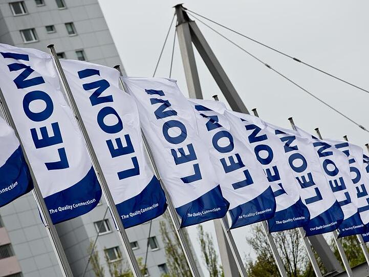 Fahnen mit dem Logo des Kabel-Herstellers Leoni wehen im Wind. Foto: Daniel Karmann/Archiv