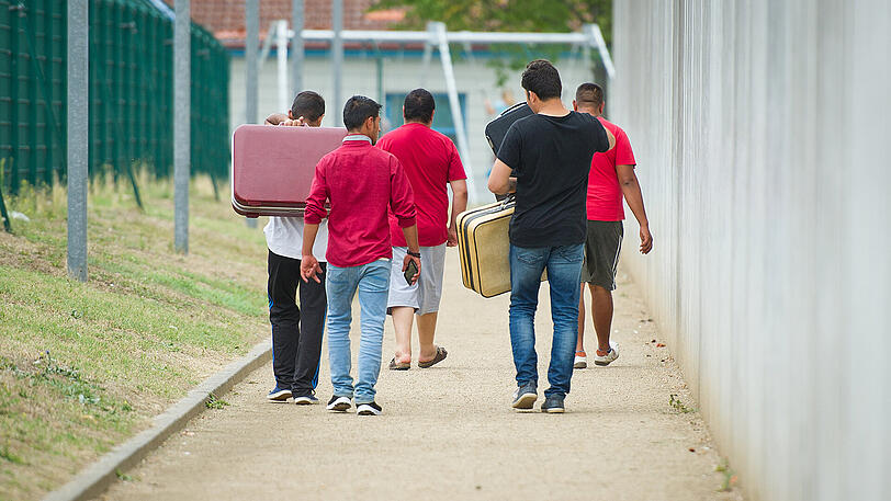 Flüchtlinge laufen mit Koffern bepackt auf einem Weg einer Erstaufnahmeeinrichtung in Ingelheim entlang.