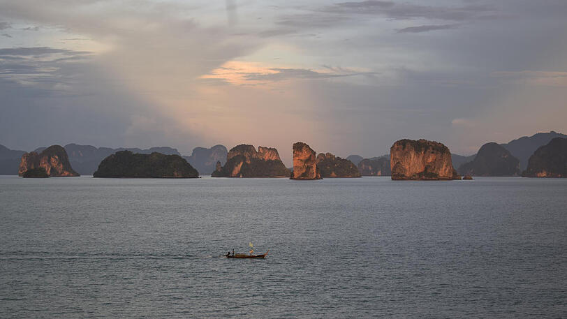 Das Orange der untergehenden Sonne entzündet die schroffen Kalksteinfelsen vor Koh Yao Noi.