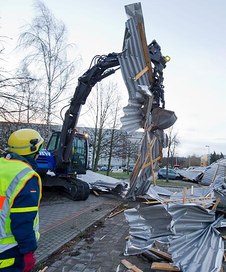 Mitarbeiter des Technischen Hilfswerks räumen das abgedeckte Dach des Supermarkts weg