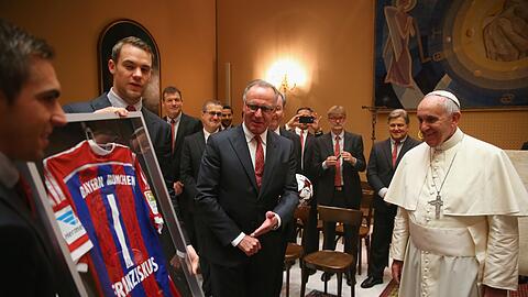 Philipp Lahm (l.) und Manuel Neuer überreichen vor den Augen von Karl-Heinz Rummenigge ein signiertes Bayern-Trikot mit dem Aufdruck Franziskus und der Nummer 1 an den Papst.