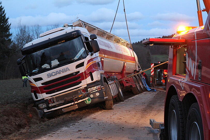 Ein Bergungsfahrzeug und zwei Kräne werden benötigt um den vollbeladenen LKW wieder auf die Straße zu ziehen.