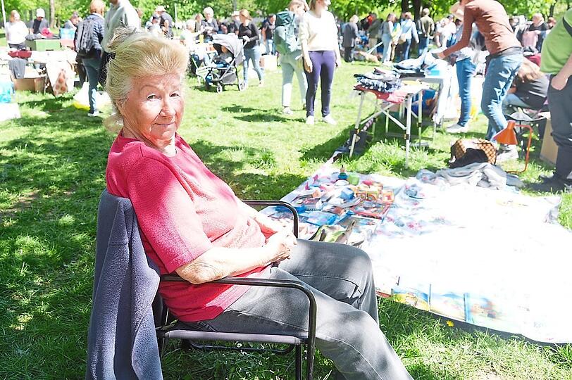Die 81-jährige Rentnerin Gerlinde hat es sich neben ihrem Flohmarktstand auf einem Stuhl im Schatten gemütlich gemacht.