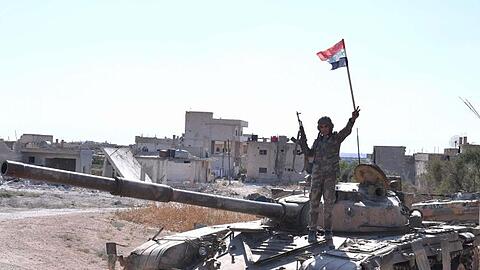 Ein syrischer Soldat zeigt auf einem Panzer das Victory-Zeichen.