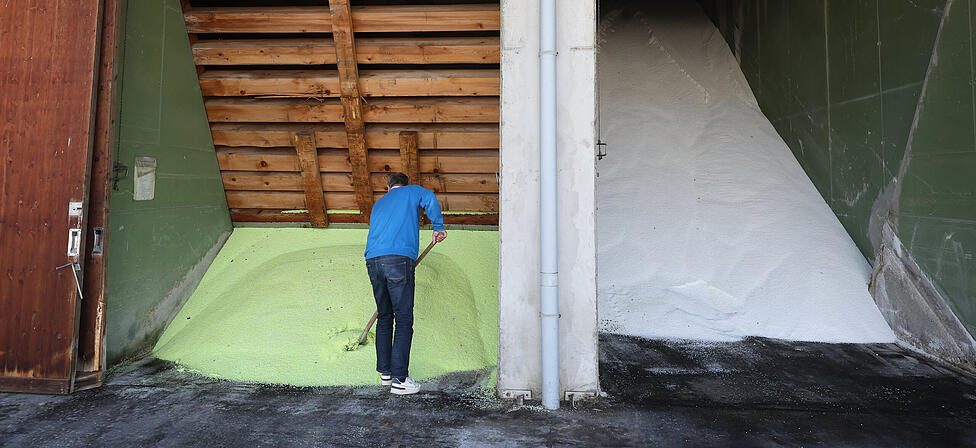 Ein Mitarbeiter schaufelt auf dem Betriebsgel&auml;nde einer BayWa Filiale in einer Halle gelagertes D&uuml;ngemittel der Sorte ALZON. Im Fr&uuml;hjahr decken sich landwirtschaftliche Betriebe mit D&uuml;nger ein, der f&uuml;r Wachstum und Ertr&auml;ge entscheidend ist, vor dem Hintergrund schwankender Gaspreise als zentralem Kostenfaktor. +++ dpa-Bildfunk +++