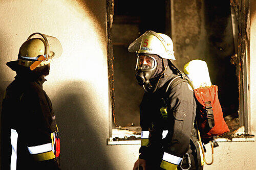 Zwei Feuerwehrmänner vor dem Fenster der ausgebrannten Wohnung in der Pastoriusstraße in Zabo.