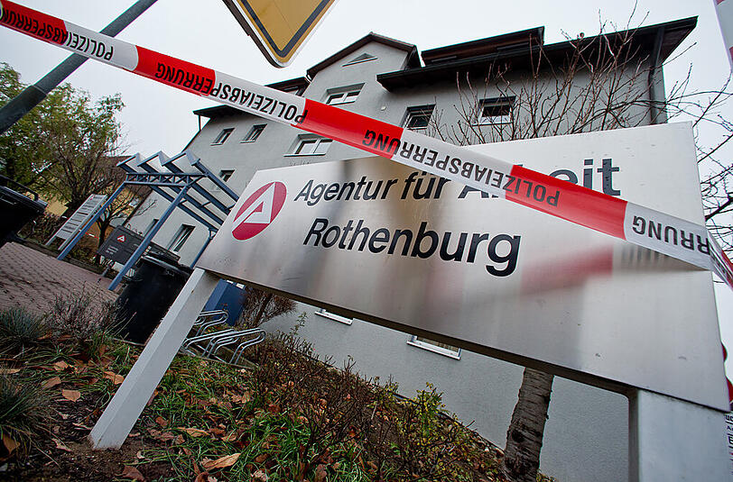Ein Absperrband der Polizei hängt am 03.12.2014 in Rothenburg ob der Tauber (Bayern) vor der Agentur für Arbeit. Dort hat ein 28 Jahre alten Mann einen Jobcenter-Mitarbeiter erstochen.