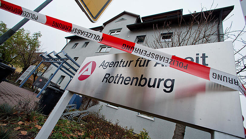 Ein Absperrband der Polizei hängt am 03.12.2014 in Rothenburg ob der Tauber (Bayern) vor der Agentur für Arbeit. Dort hat ein 28 Jahre alten Mann einen Jobcenter-Mitarbeiter erstochen. Ein Absperrband der Polizei hängt am 03.12.2014 in Rothenburg ob der Tauber (Bayern) vor der Agentur für Arbeit. Dort hat ein 28 Jahre alten Mann einen Jobcenter-Mitarbeiter erstochen.
