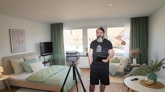 Michael Perkmann in einem Neuhauser Einzimmer-Apartment, das er bald vermietet. Links von ihm: eine Hightech-360-Grad-Kamera für 4.500 Euro. Sie ermöglicht Miet- oder Kaufinteressenten einen digitalen, dreidimensionalen Rundgang.