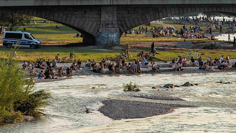 Die Verhältnisse auf der Isar haben sich entspannt: Hier sitzen Münchner auf einer Kiesbank gegenüber des Deutschen Museum in der Abendsonne.
