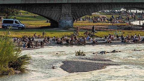 Die Verhältnisse auf der Isar haben sich entspannt: Hier sitzen Münchner auf einer Kiesbank gegenüber des Deutschen Museum in der Abendsonne.