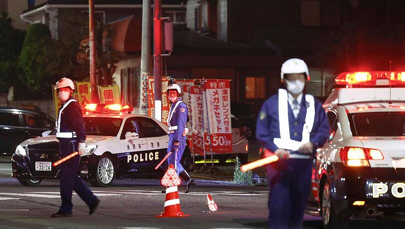 Polizisten stehen Wache auf einer Straße in der Nähe eines Gebäudes, in dem sich ein Mann verschanzt hat.