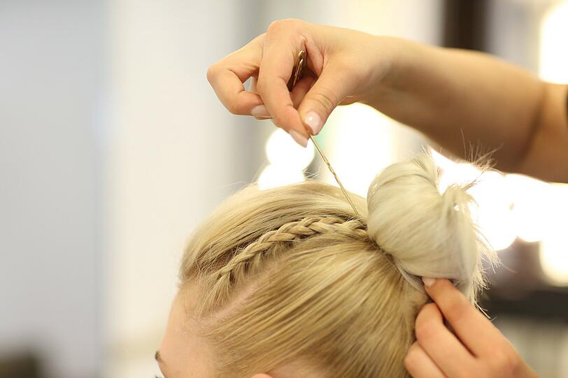 Bei kürzeren Haaren wird ein Duttkissen über den Pferdeschwanz geschoben und die Haare darüber verteilt.