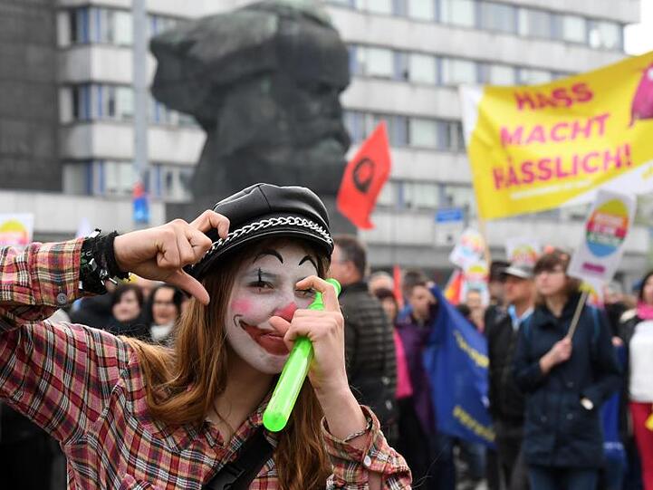 Teilnehmer einer Demonstration unter dem Motto "Aufstehen gegen Rassismus", darunter auch diese als Clown geschminkte Frau, haben sich am 1. Mai im Zentrum von Chemnitz versammelt.
