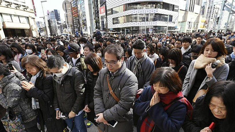 Menschen gedenken im Ginza-Einkaufsviertel in Tokio der Opfer, die 2011 bei der Natur- und Atomkatastrophe von Fukushima getötet wurden.