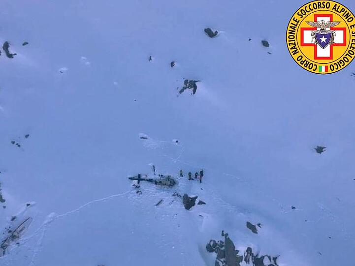 Dieses vom italienischen Bergrettungsdienst zur Verfügung gestellte Bild zeigt eine Gruppe von Bergrettern, die neben den Trümmern des Hubschraubers stehen.