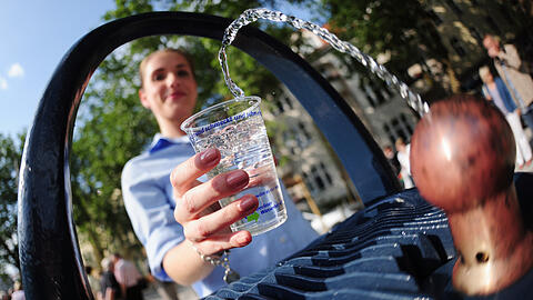 Eine junge Frau nimmt Wasser von einem Trinkbrunnen. Die Trinkwasserpreise für Verbraucher in Deutschland sind in den vergangenen Jahren deutlich gestiegen.