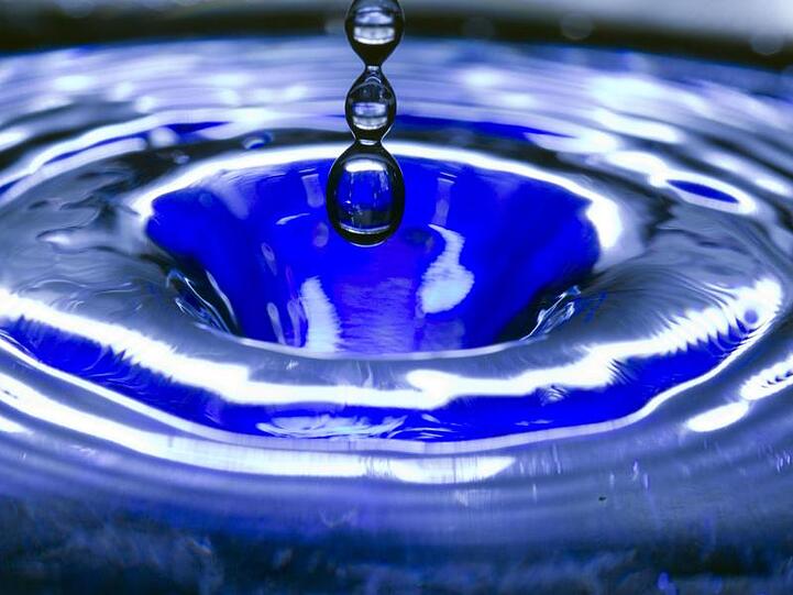 Ein Wassertropfen fällt in eine blaue Wasserschüssel. Foto: Jens Büttner/zb/dpa/Symbolbild