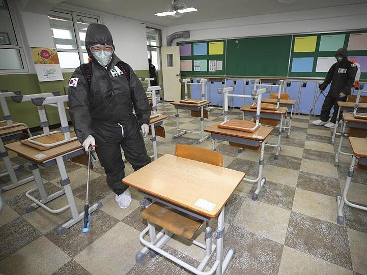 Soldaten in Schutzanzügen versprühen Desinfektionsmittel in einem Klassenzimmer der Gyeongu-Mittelschule, um der Ausbreitung des neuartigen Coronavirus entgegenzuwirken.