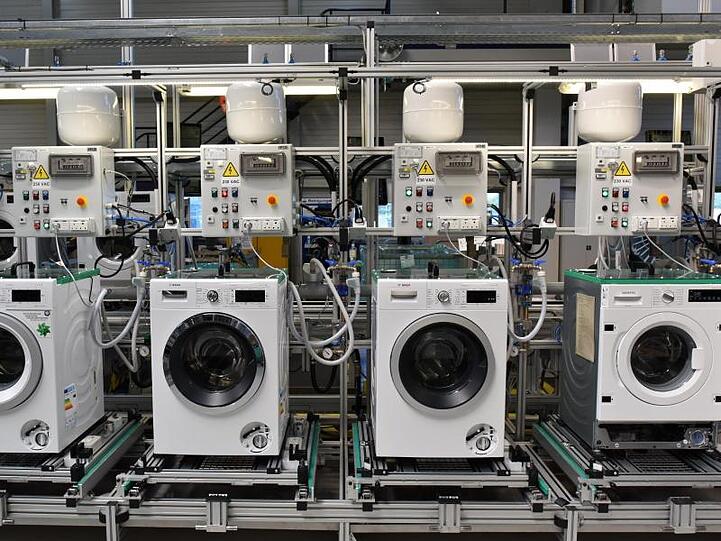 Waschmaschinen stehen in einer Produktionsstätte nebeneinander. Foto: Ralf Hirschberger/Archiv