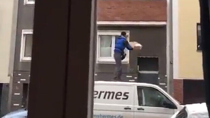 Mehrmals versucht der Hermes-Bote, vom Dach seines Lieferwagens aus, ein Paket auf den Balkon im 1. Stock zu werfen.