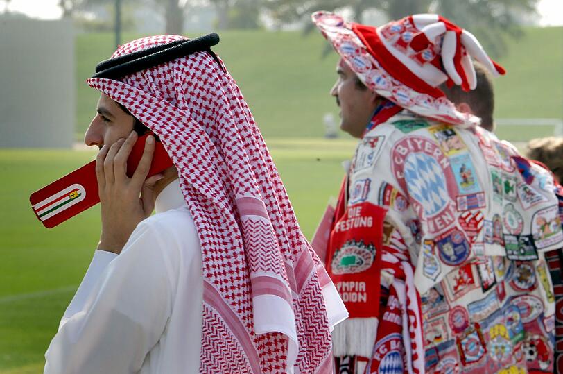 Da schaut der Araber: Ein Fan aus Katar steht neben einem Bayern-Anhänger. Die beiden beobachten das Training des FC Bayern München in Doha.