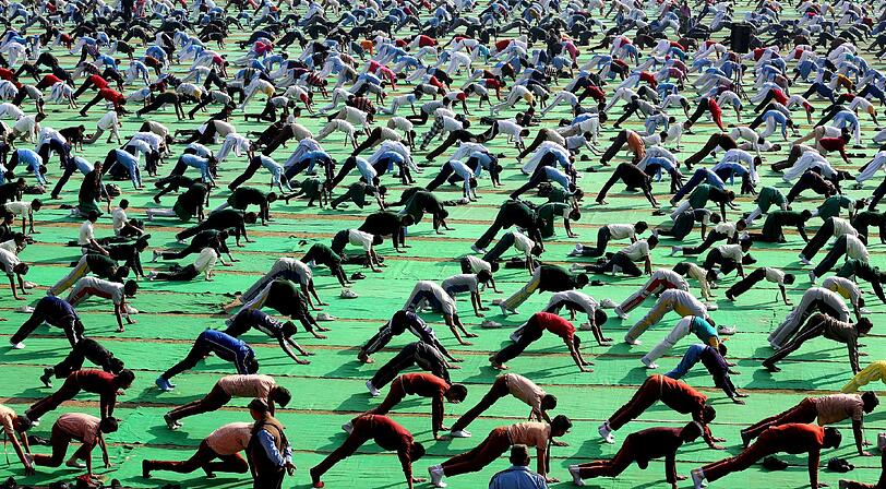 ... und hunderte machen es nach. In Bhopal machen die Menschen zum 150. Geburtstag von Swami Vivekanand Yoga. Der hinduistische Mönch gilt als einer der Urväter der Yoga-Lehre.