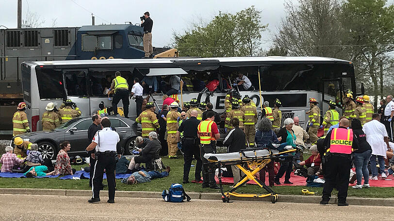 Feuerwehrleute helfen verletzten Passagieren aus einem verunfallten Reisebus, nachdem der Bus am 07.03.2017 in Biloxi (USA) mit einem Zug kollidiert ist.