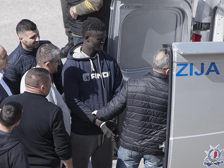 Migranten werden von der maltesischen Polizei in Gewahrsam genommen.