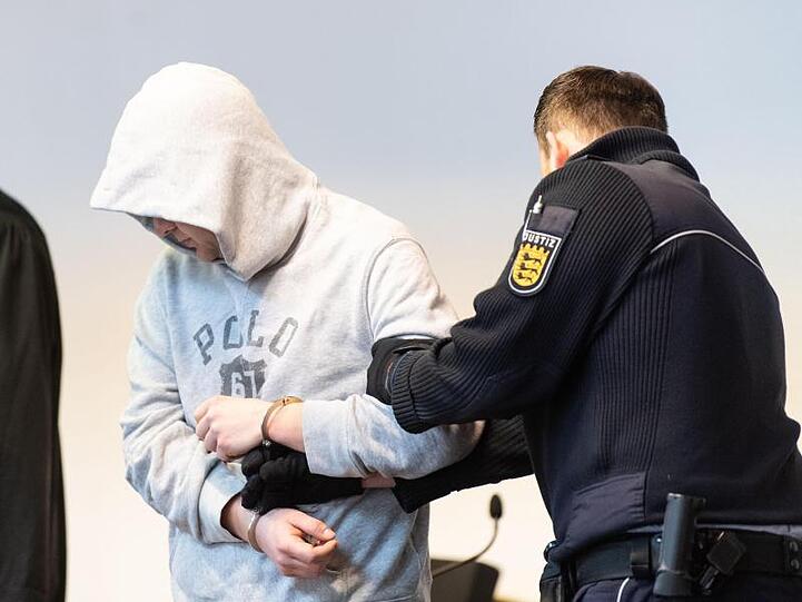 Der Angeklagte wird von einem Justizbeamte in den Sitzungssaal des Landgerichts gebracht.