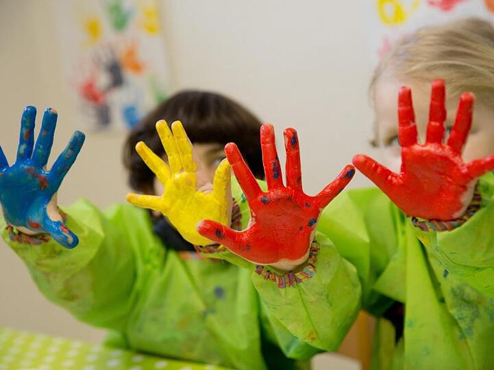 Zwei Kinder spielen mit Fingerfarben im Atelier eines Kindergartens. Foto: Daniel Karmann/dpa/Archiv