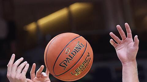 Spieler greifen nach einem Basketball.