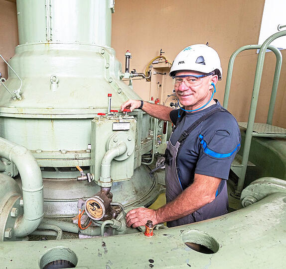 Kraftwerker Josef Hobmeier steht im Maschinenhaus im Wasserkraftwerk Altheim neben einer Turbine.