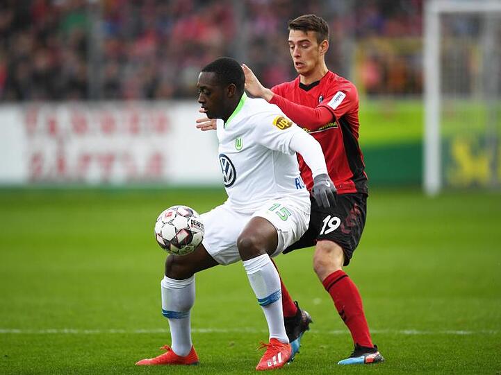 Wolfsburgs Jerome Roussillon (l) im Duell mit Freiburgs Janik Haberer.