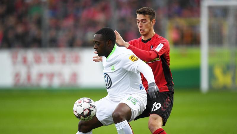 Wolfsburgs Jerome Roussillon (l) im Duell mit Freiburgs Janik Haberer.