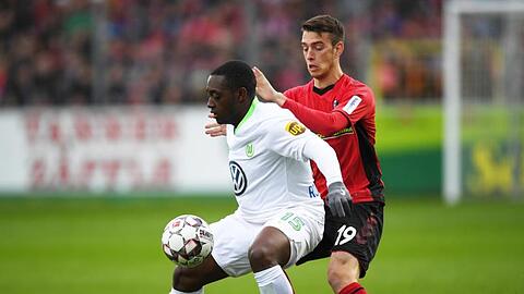Wolfsburgs Jerome Roussillon (l) im Duell mit Freiburgs Janik Haberer.